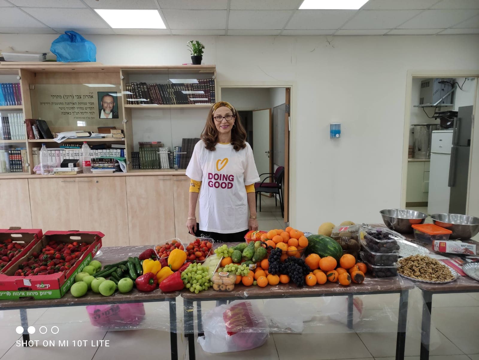 מזל מעבירה סדנת עיצוב פירות ליד שולחן מלא פירות ויצירות